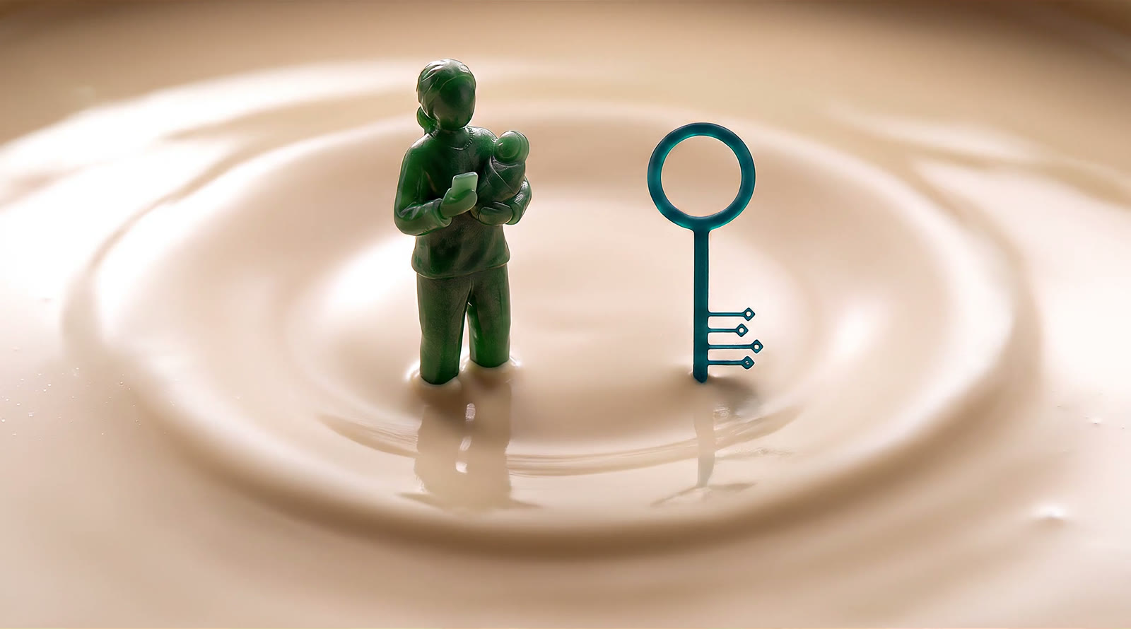 The same carved emerald statuette standing upright, the swaddled infant held to her shoulder and a small phone at her chest, beside a teal key rising from the ivory pool.